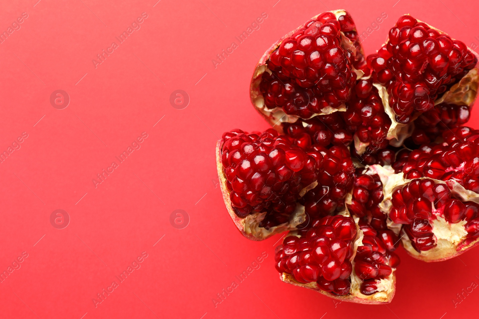 Photo of Cut fresh pomegranate on red background, top view. Space for text