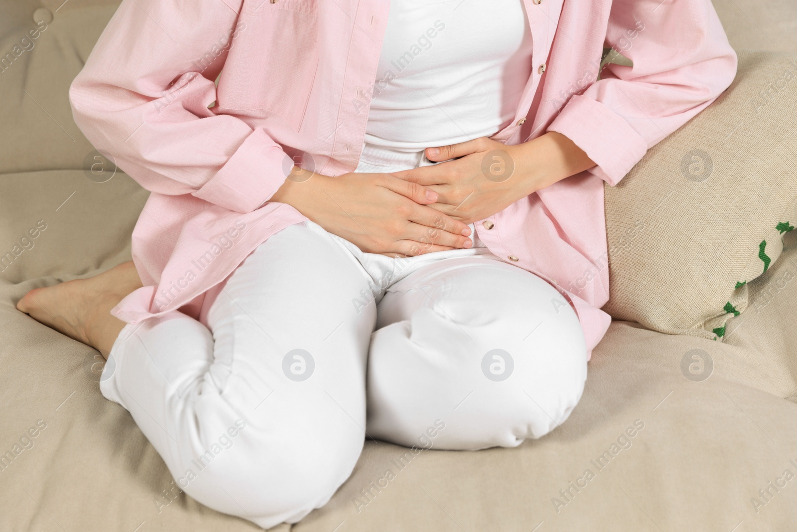 Photo of Woman suffering from cystitis on sofa at home, closeup