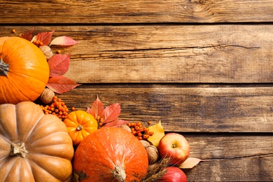 Flat lay composition with ripe pumpkins and autumn leaves on wooden table, space for text. Happy Thanksgiving day