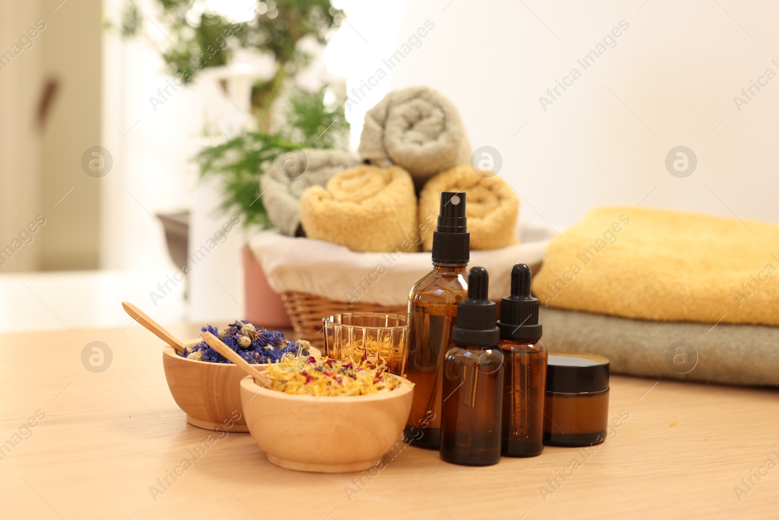 Photo of Dry flowers, bottles of essential oils and jar with cream on wooden table indoors. Spa time