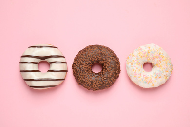 Photo of Delicious glazed donuts on pink background, flat lay