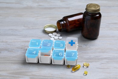 Weekly pill box with medicaments on wooden table