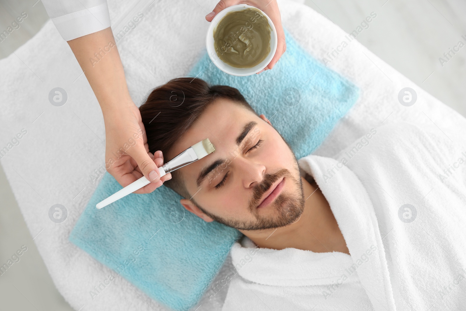 Photo of Cosmetologist applying mask on client's face in spa salon, above view