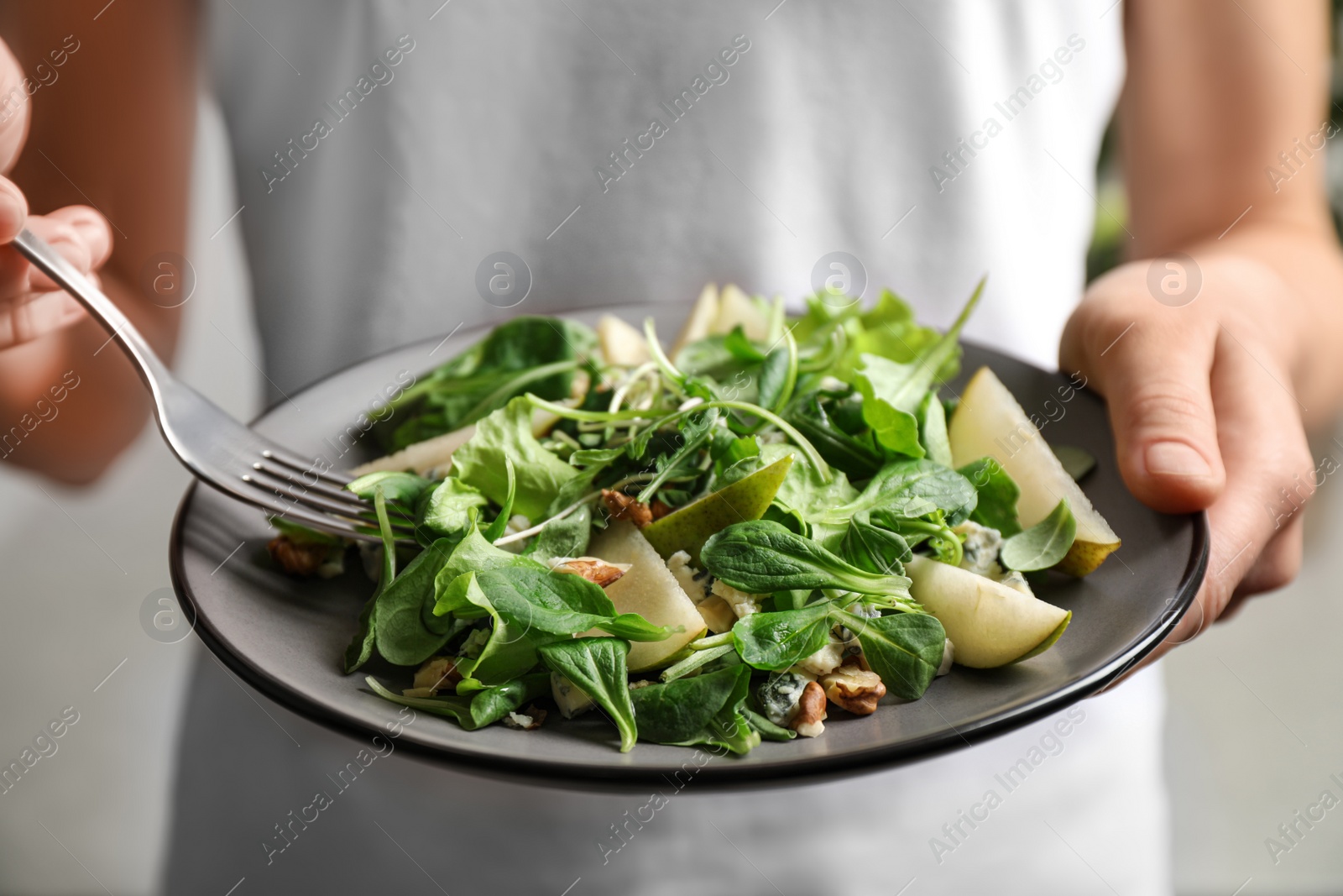 Photo of Woman with tasty pear salad on light background, closeup