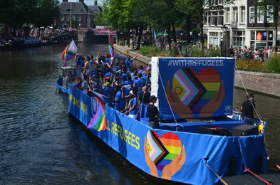 Photo of AMSTERDAM, NETHERLANDS - AUGUST 06, 2022: Many people in boat at LGBT pride parade on river