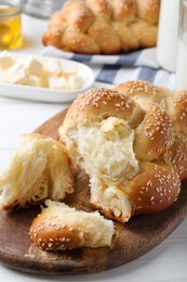 Homemade braided bread with sesame seeds on white wooden table, closeup. Traditional challah