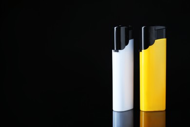 Photo of White and yellow plastic cigarette lighters on black background, space for text