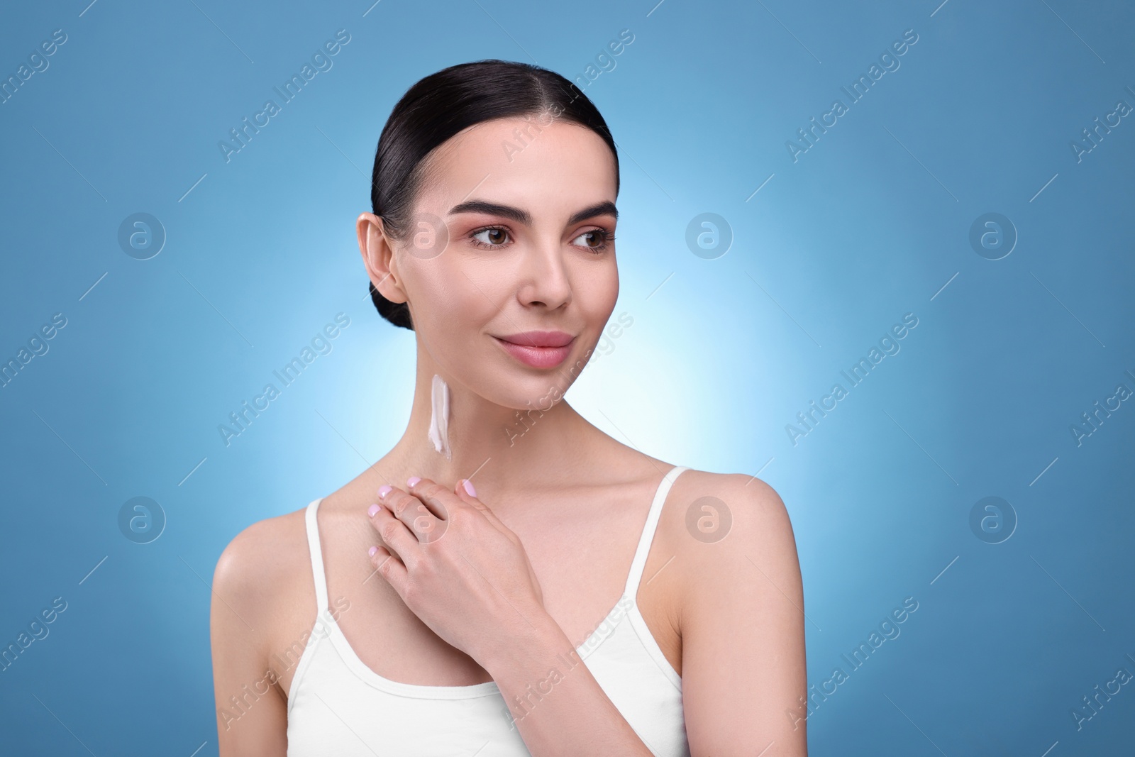 Photo of Beautiful woman with smear of body cream on her neck against light blue background. Space for text