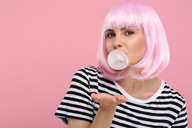 Photo of Beautiful woman blowing bubble gum on pink background, space for text