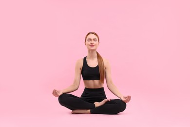 Beautiful young woman practicing yoga on pink background. Lotus pose