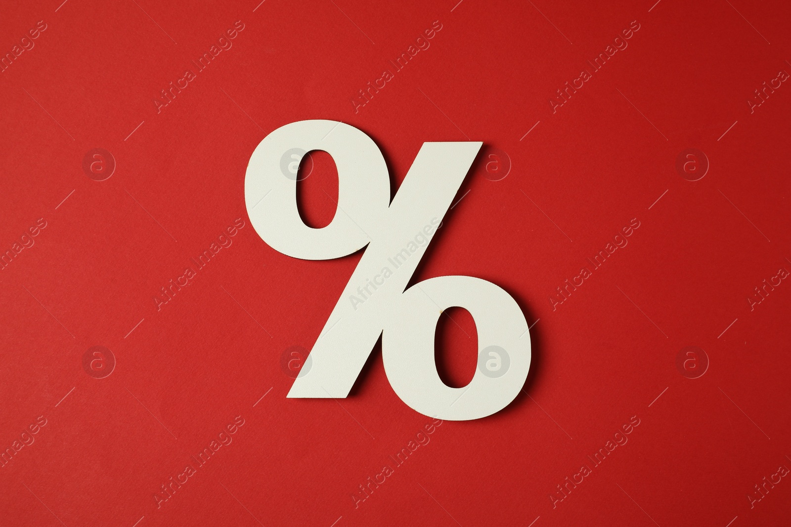 Photo of White percent sign on red background, top view