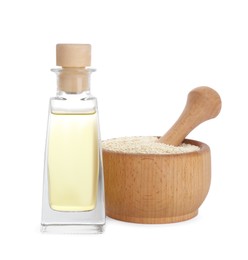 Photo of Glass bottle of fresh sesame oil, mortar with pestle and seeds isolated on white