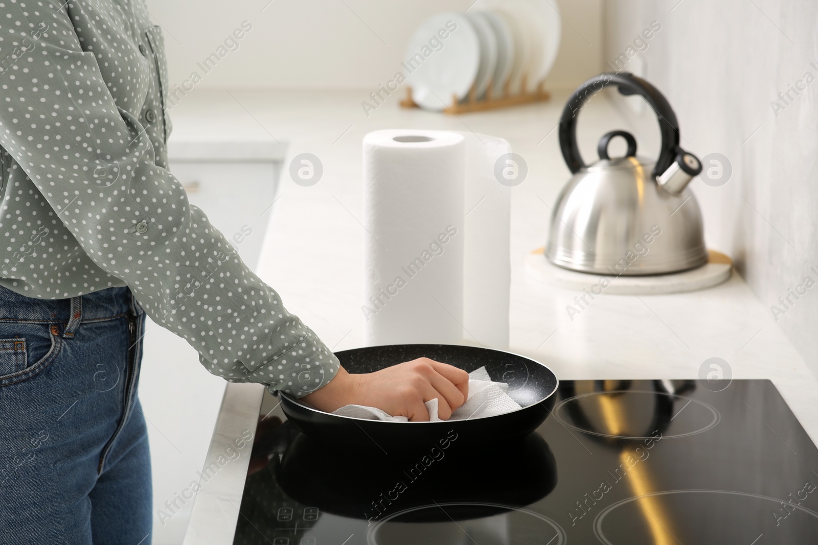 Photo of Woman wiping frying pan with paper towel in kitchen, closeup