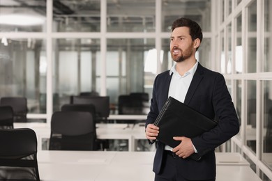 Photo of Happy real estate agent with leather portfolio indoors. Space for text