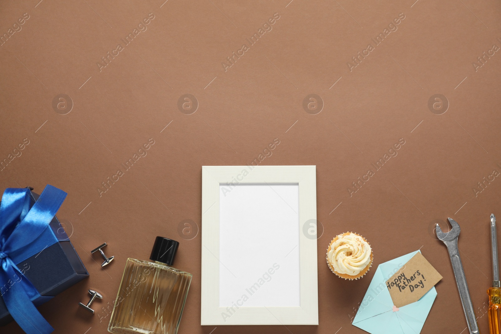 Photo of Empty photo frame, gift box and men accessories on brown background, flat lay with space for text. Father's day celebration