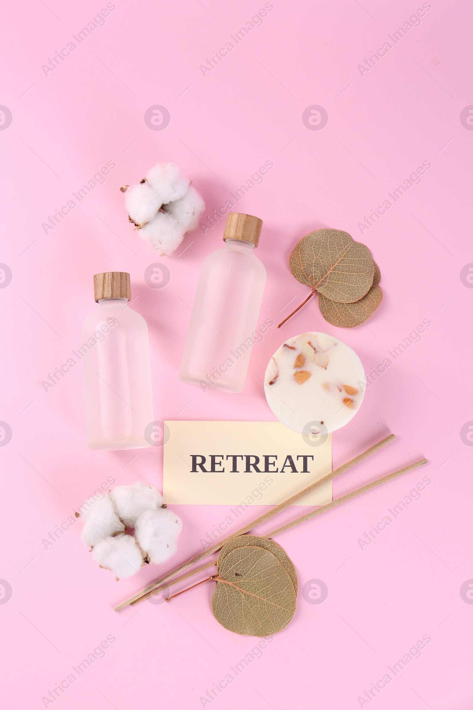 Photo of Retreat concept. Flat lay composition with card, bottles of cosmetic products and cotton flowers on pink background