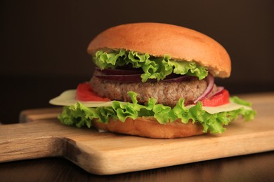 Photo of Tasty burger with vegetables, patty and cheese on wooden table, closeup