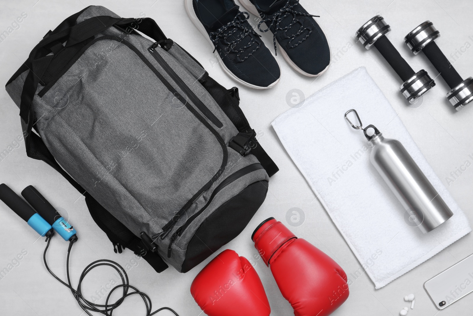 Photo of Gym bag and sports equipment on white background, flat lay