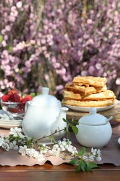 Beautiful spring flowers, freshly baked waffles and ripe strawberries on table served for tea drinking in garden