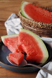 Photo of Sliced fresh juicy watermelon and spoon on wooden table, closeup