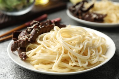 Tasty cooked rice noodles with meat on grey table
