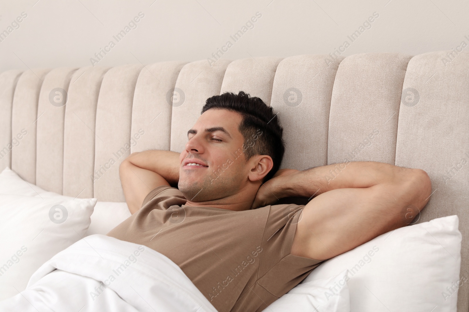 Photo of Happy man lying in bed at home