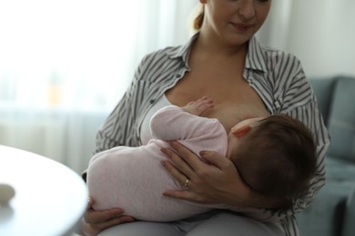 Photo of Young woman breastfeeding her baby at home