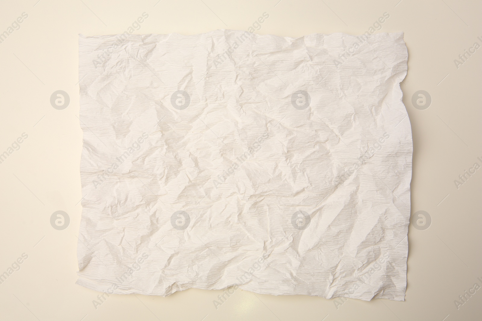 Photo of Sheet of crumpled paper on beige background, top view