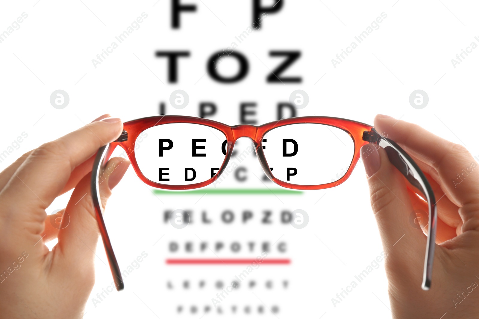 Image of Woman holding glasses, closeup. View through lenses on eye chart, white background