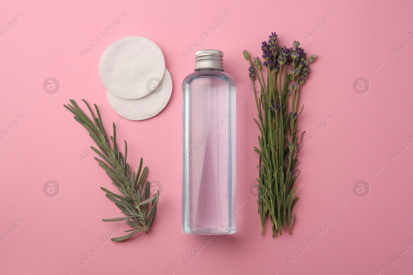 Photo of Flat lay composition with bottle of makeup remover and cotton pads on pink background