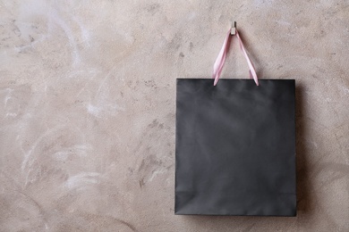 Photo of Paper shopping bag with handles hanging on color wall. Mock up for design