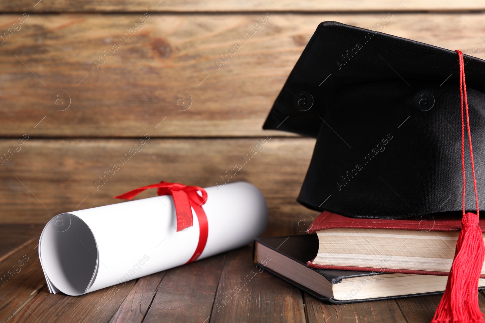 Photo of Graduation hat, books and student's diploma on wooden table