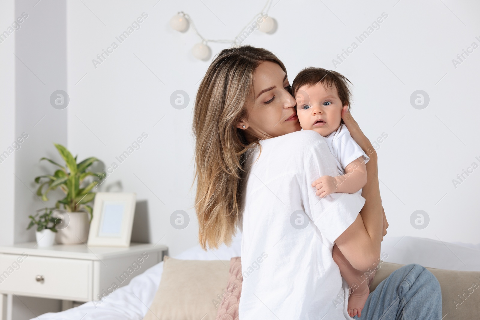 Photo of Mother kissing her cute little baby in bedroom