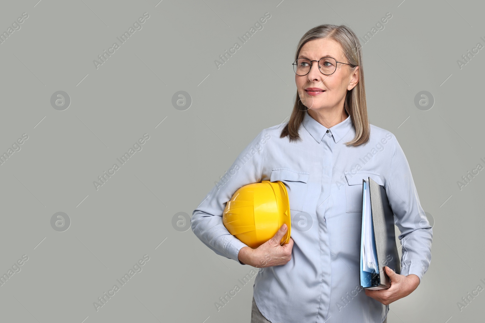 Photo of Architect with hard hat and tube on grey background, space for text