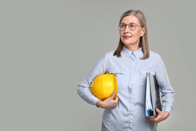 Architect with hard hat and tube on grey background, space for text