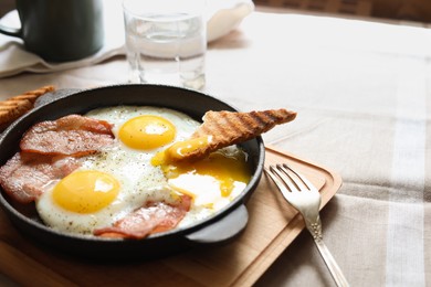Photo of Tasty fried eggs with bacon and toast on table, closeup. Space for text