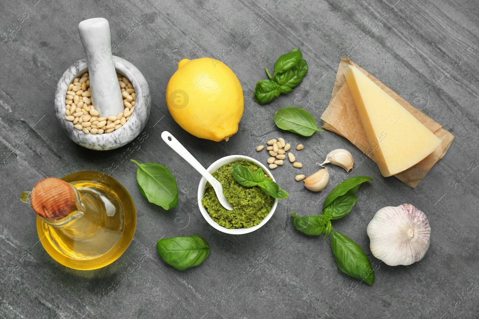 Photo of Delicious pesto sauce and ingredients on grey table, flat lay