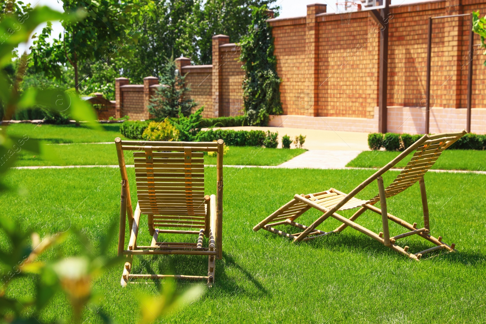 Photo of Wooden deck chairs in beautiful garden on sunny day