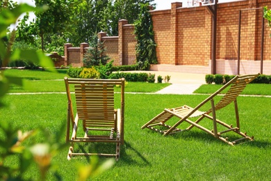 Wooden deck chairs in beautiful garden on sunny day