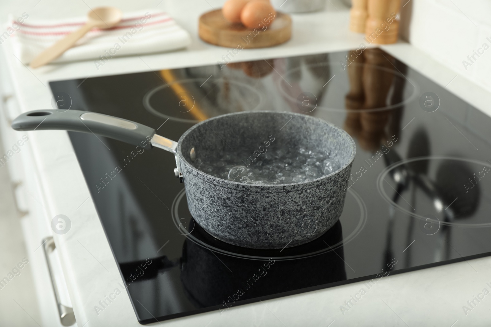 Photo of Saucepan with boiling water on electric stove in kitchen. Cooking utensil