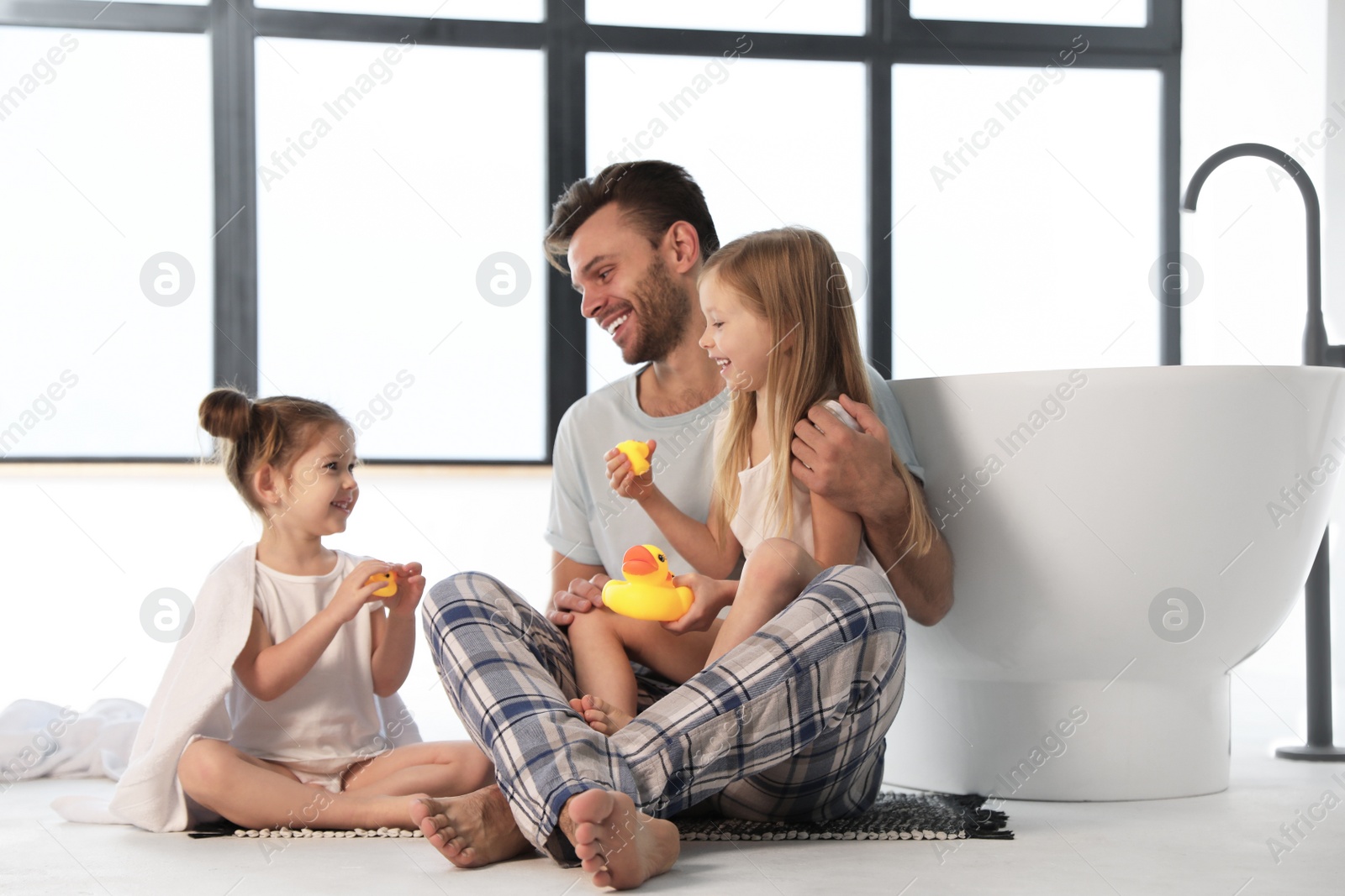 Photo of Father with little daughters near tub in bathroom