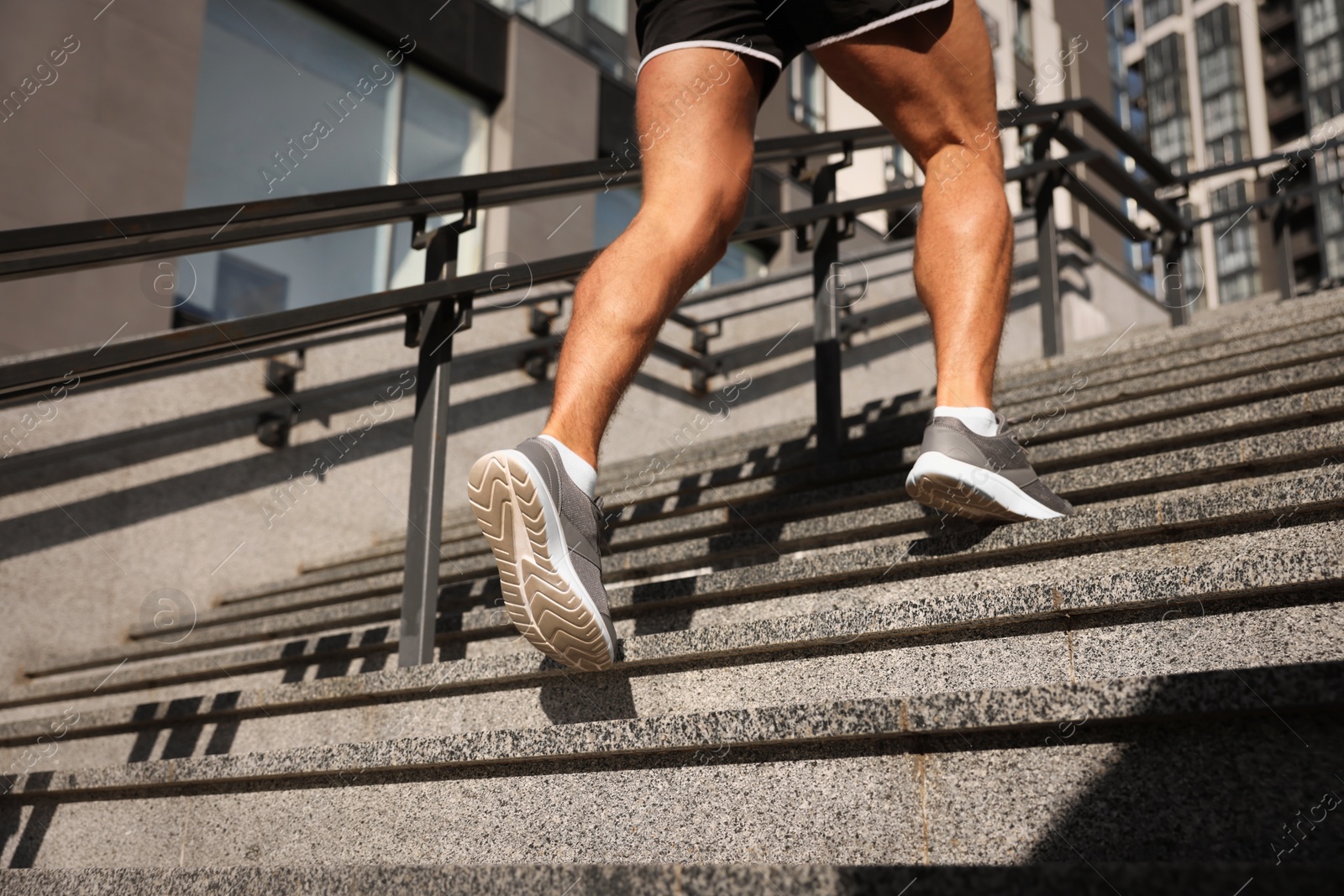 Photo of Man running up stairs outdoors on sunny day, closeup. Space for text