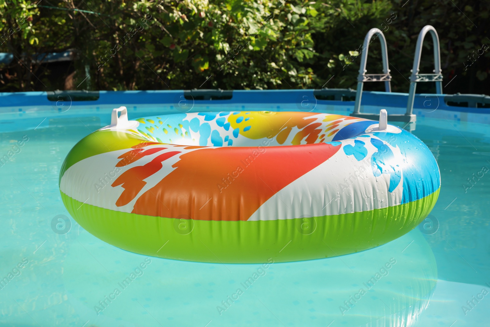 Photo of Inflatable ring floating on water in above ground swimming pool outdoors, closeup