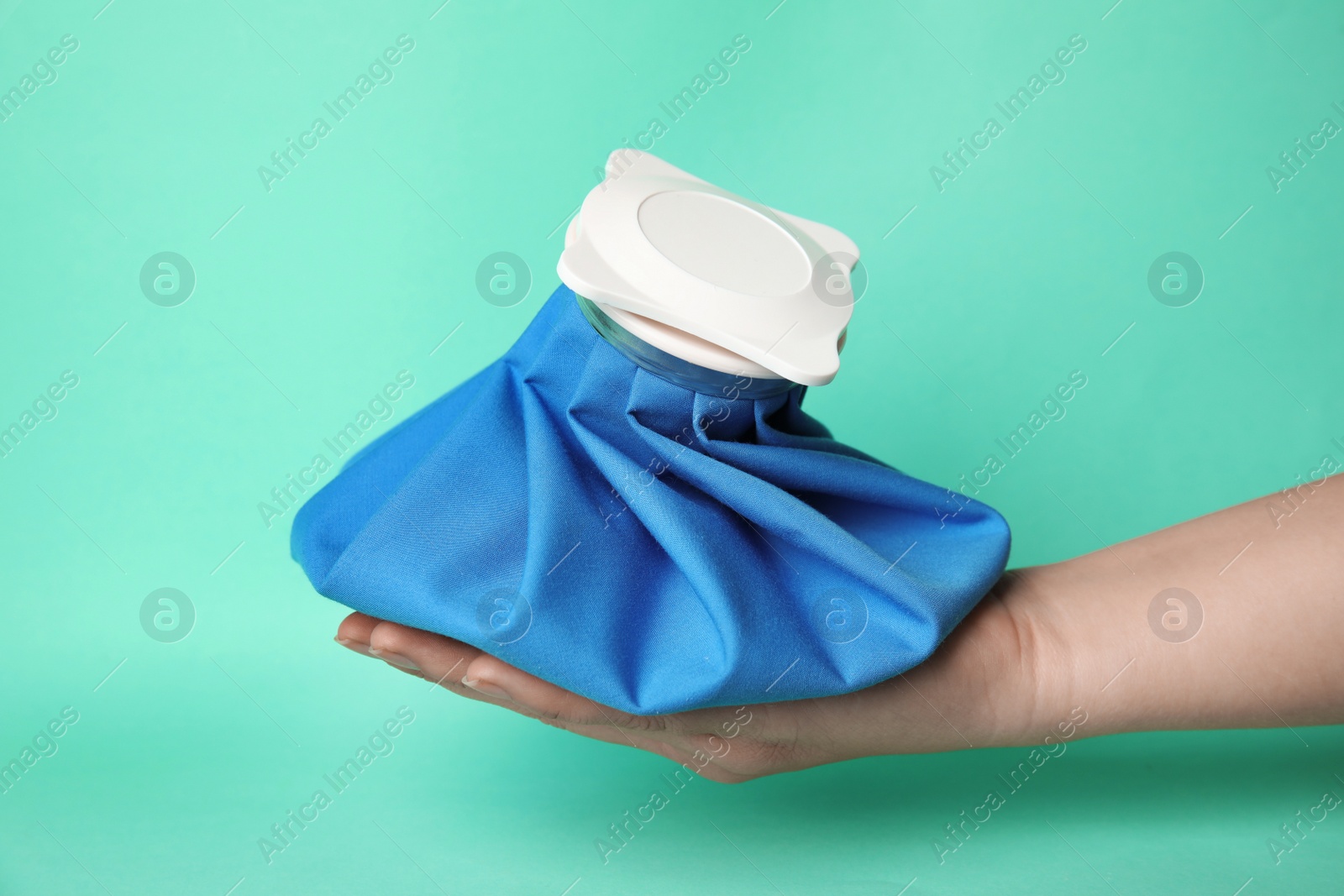 Photo of Woman holding ice pack against turquoise background, closeup