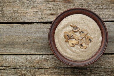 Photo of Delicious mushroom cream soup on wooden table, top view. Space for text