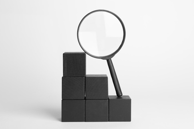 Magnifying glass and stairs made with black cubes on white background. Search concept