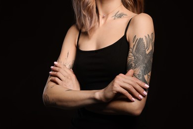 Photo of Beautiful woman with tattoos on body against black background, closeup