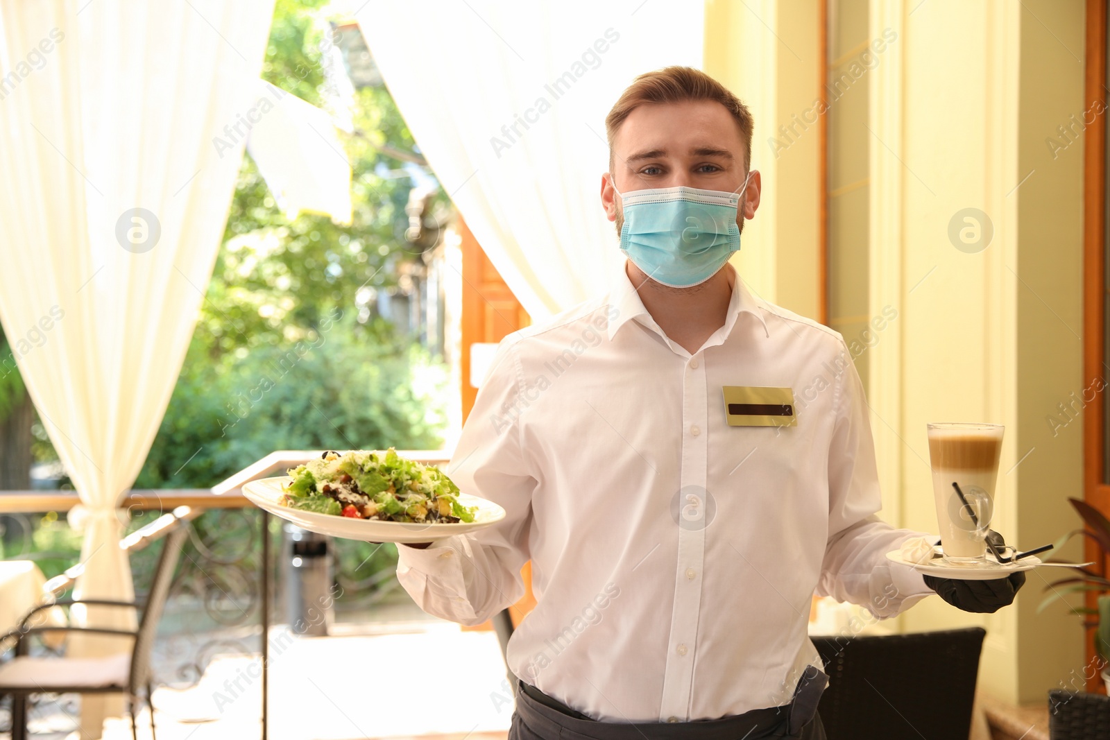 Photo of Waiter serving salad and coffee in restaurant. Catering during coronavirus quarantine