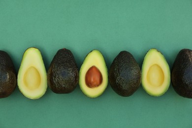 Photo of Tasty whole and cut avocados on turquoise background, flat lay