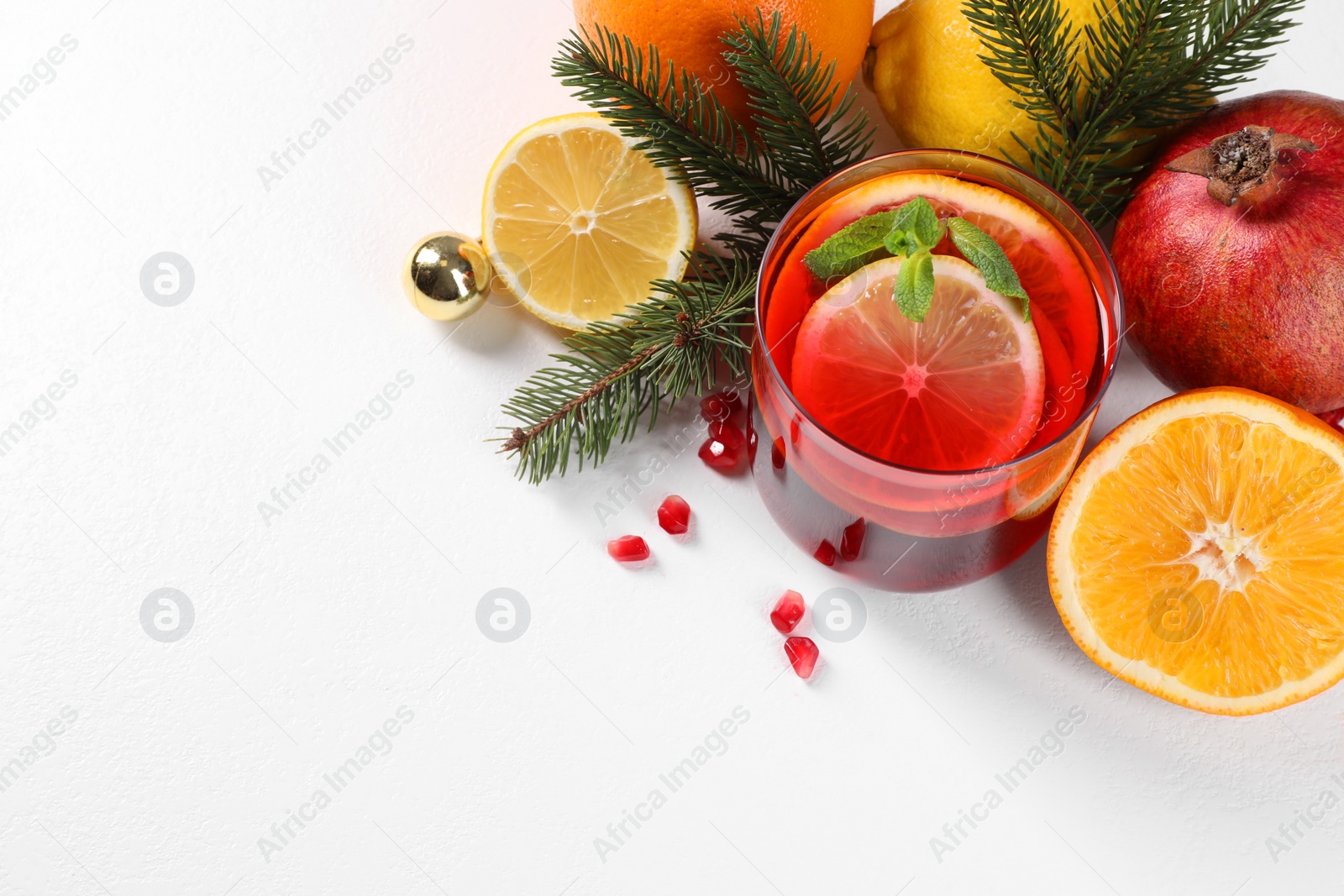 Photo of Christmas Sangria drink in glass, fir branches and fruits on white background, above view. Space for text